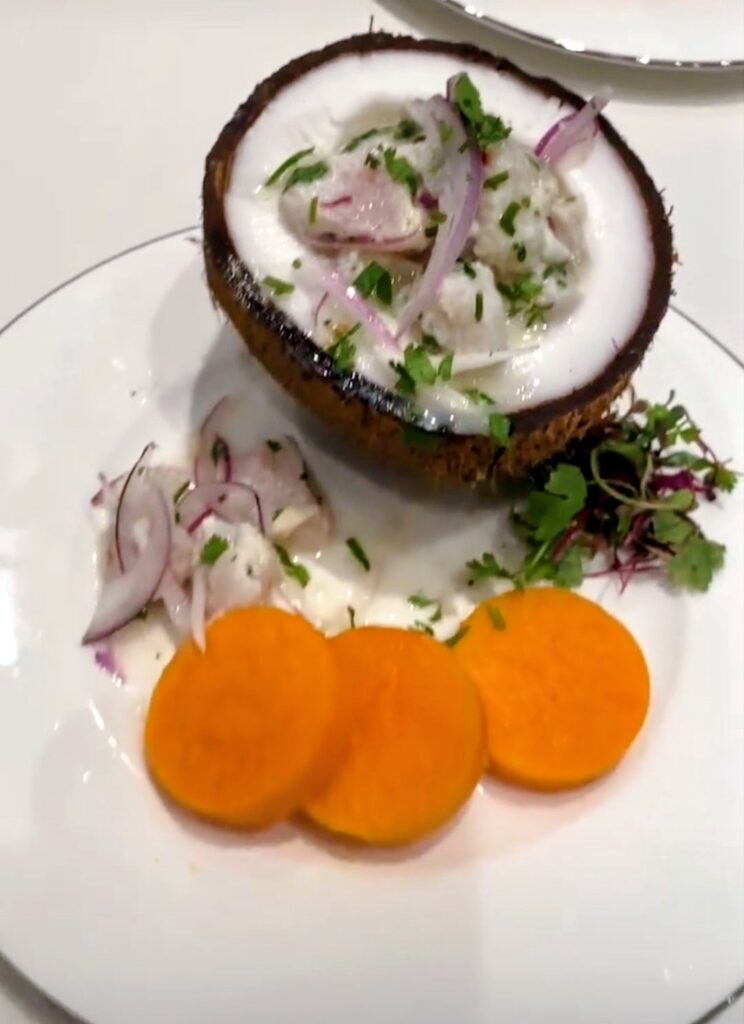 Seafood served in a coconut shell with colorful accompaniments