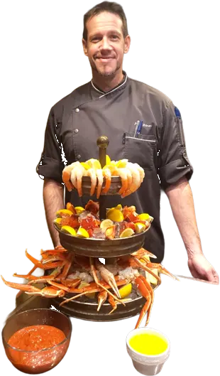 Chef Philip Ritman of A Family Cooking presenting a seafood platter with crab legs and shrimp