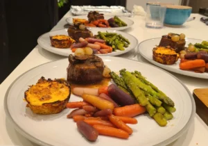 Filet mignon with mushrooms, asparagus, glazed carrots, and cauliflower muffin served on dinner plates